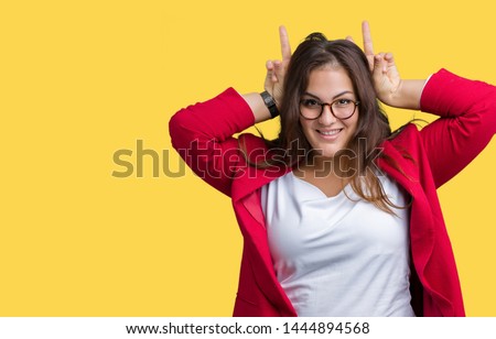 Beautiful plus size young business woman wearing elegant jacket and glasses over isolated background Posing funny and crazy with fingers on head as bunny ears, smiling cheerful