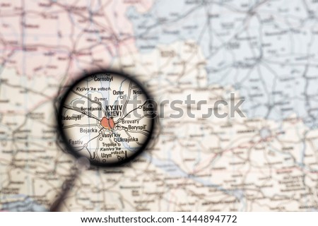 Kiev Ukraine capital close-up through a magnifying glass on the background of a blurred geographical map of Europe. The concept of news and events screensaver.