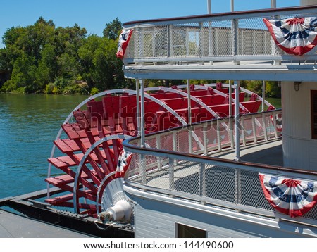 Red Riverboat Paddle Wheel in a River with Trees Royalty-Free Stock Photo #144490600
