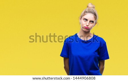 Young beautiful blonde and blue eyes woman wearing blue t-shirt over isolated background making fish face with lips, crazy and comical gesture. Funny expression.