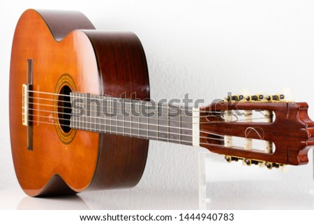 a rare classical acoustic guitar from the 70s small sized vintage used look with scratches in the dark wood macro lens exposure isolated on white background in studio closeup of the parts
