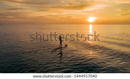 Drone view of a male doing pedal boarding while the sun is setting.  
Picture taken on November 21st 2018.