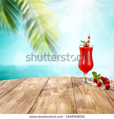Fresh cold summer drink of raspberry fruits and landscape of summer sea with palm. 