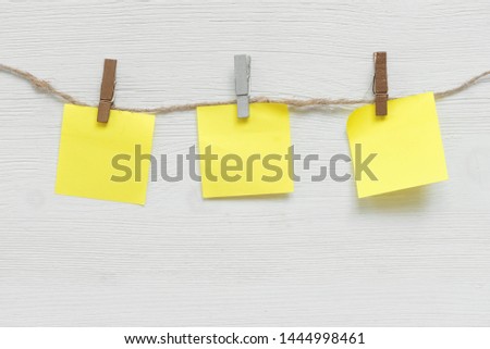 Blank paper stickers with copy space on a clothespin on a rope on a white table background. To do list template.