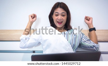 Successful positive young woman with watching live stream online on laptop and celebrating victory of favourite team. Asian women with online purchases successfully.