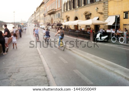 Blur photo of tourists walking, sightseeing, and biking on Florence street along side of Arno River, in the historical Old Town of Florence, Tuscany, Italy.