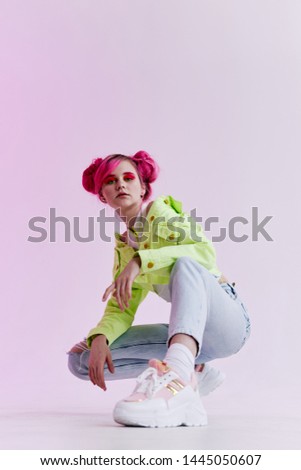 a woman with pink hair in a green jacket is sitting