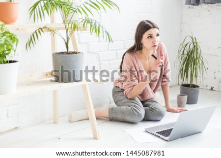 Young woman sits on the floor in a Scandinavian apartment interior with a laptop, studying law, freelance girl at work, distance learning student, online employment, paperwork and outsourcing concept
