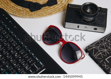 accessories for work with travel on the beach: laptop, notebook, straw hat, vintage camera, pen, sunglasses on a white background, top view.