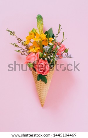 Flat lay Ice Cream Cones with colorful bouquet on pink background, copy space