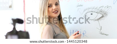 Makeup Vlogger Recording Beauty Tutorial on Camera. Online Training Concept. Beautiful Caucasian Woman Recording Video Blog, Drawing Human Eye on Whiteboard. Cosmetics Applying Technique Workshop