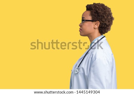 Young african american doctor woman wearing medical coat over isolated background looking to side, relax profile pose with natural face with confident smile.