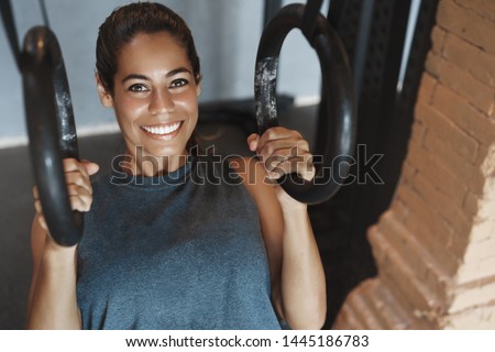 Close-up satisfied sweaty attractive smiling woman doing crossfit gymnastic rings exercise push-ups, look motivated delighted, wear activewear, training session alone in gym, train muscles