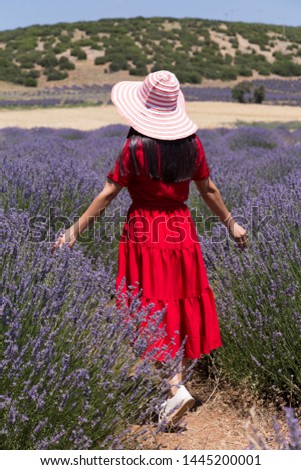 the woman wearing red dress and wicker hat in the lavender field.