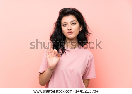 Young woman over isolated pink background showing an ok sign with fingers