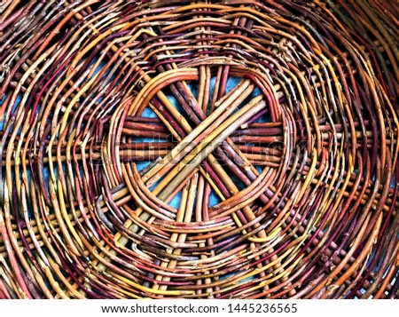 Top view of the bottom of the basket, hand-woven from colorful rods as the background