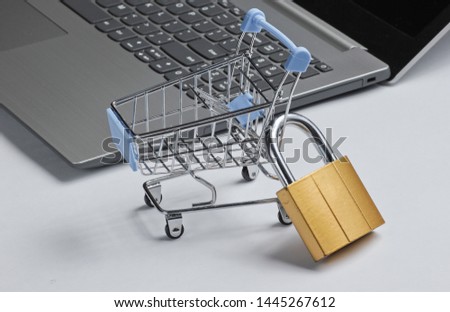 Restriction on online shopping minimalistic concept. Mini shopping trolley with lock, laptop on white background