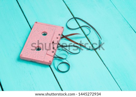 Music lover minimalism concept. Retro style 80s. Pink audio cassette with film on a blue wooden background.