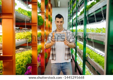 Agronomist with tablet. Promising dark-haired agronomist standing in the greenhouse holding tablet