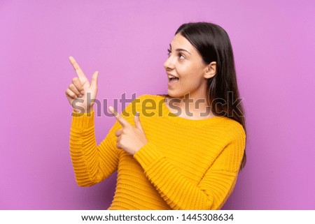 Young woman over isolated purple background pointing with the index finger a great idea