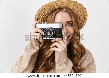 Photo of a happy pleased cute young teenage girl posing isolated over white wall background holding camera photographing.