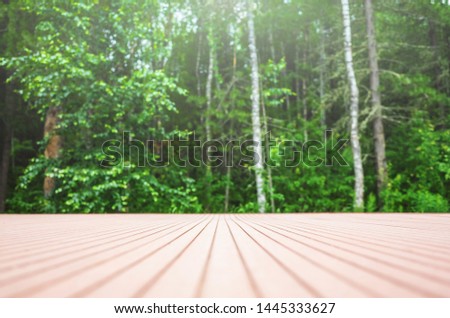 Summer forest background - in the foreground a wooden surface, in the background - a blurred forest. Place to insert items, text, logo. Minimalism.