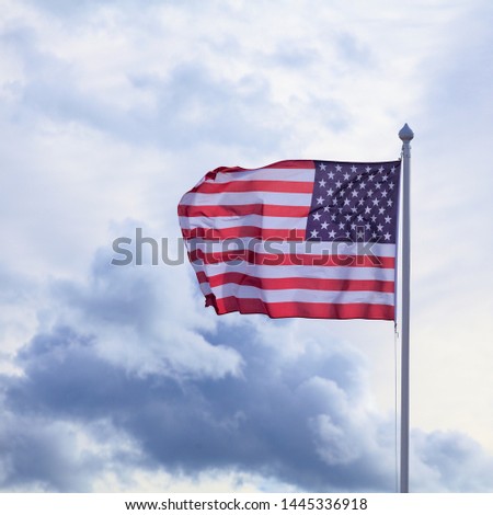 Flag of the USA wawing on the wind and white clouds on the backround