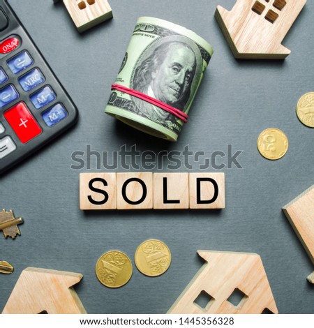 Wooden houses, a calculator, keys, coins and blocks with the word Sold. Concept of selling a house, apartment. Market of real estate. Trade of property. Affordable housing. Realtor Services. Flat lay