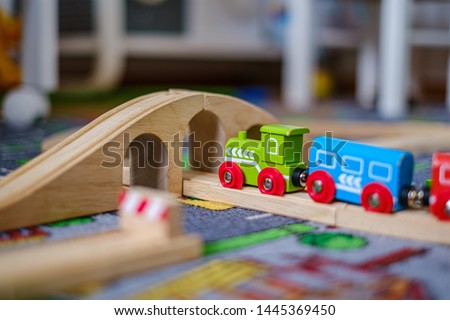 baby hands playing and learning with wooden train set on wooden rails on a carpet in nursery at home