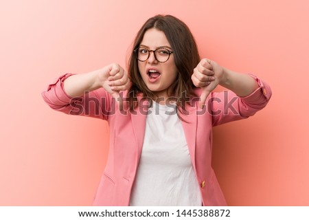 Young plus size business caucasian woman showing thumb down and expressing dislike.