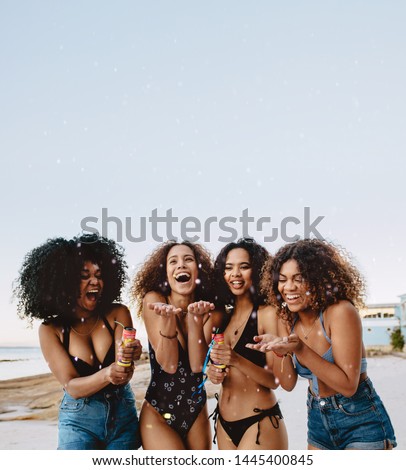 Group of girls in bikini enjoying on the beach. Happy young women playing confetti at the beach.