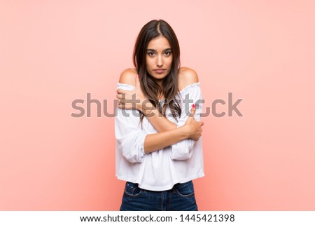 Young woman over isolated pink background freezing