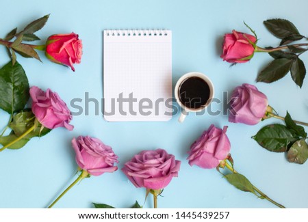notepad cup of coffee and a bouquet of flowers on a blue background, business idea or concept