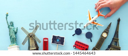 holidays image of traveling concept with accessories and world symbols over blue background. top view, flat lay