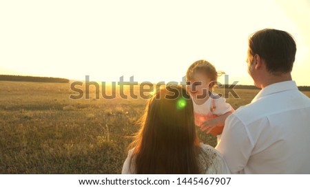 Dad and mom playing with little daughter in her arms at sunset. family walks with a child at sunset. father playing with his daughters resting in the park. concept of happy family and childhood.
