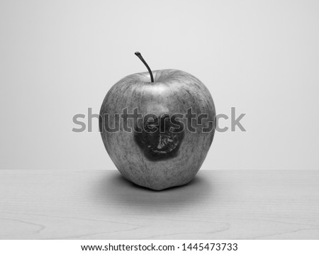 Bruised apple starting to rot on wood table. Black and white. Concept: rotten to the core, one bad apple...