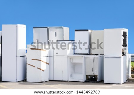 Old fridges freezers refrigerant gas at refuse dump skip recycle stacked pile help environment reduce pollution white silver blue sky Royalty-Free Stock Photo #1445492789