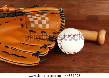 Baseball glove, bat and ball on wooden background