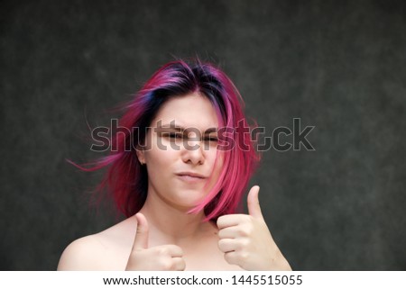 Close-up portrait of a young pretty teen girl with beautiful purple hair on a gray background in the studio. Smiles with emotions