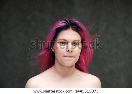 Close-up portrait of a young pretty teen girl with beautiful purple hair on a gray background in the studio. Smiles with emotions
