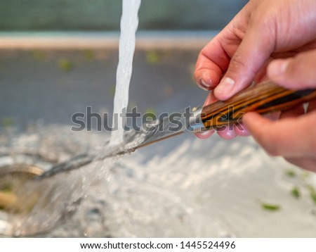 Man's hands washing under the tap a kitchen knife