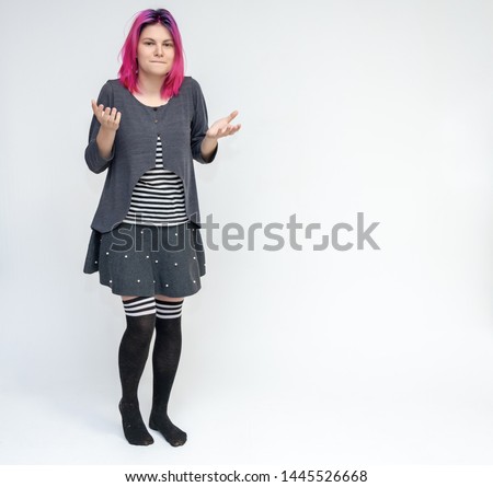 Full-length portrait of young pretty teenager girl in gray suit with beautiful purple hair on a white background in the studio. Talking, smiling, showing hands with emotions.