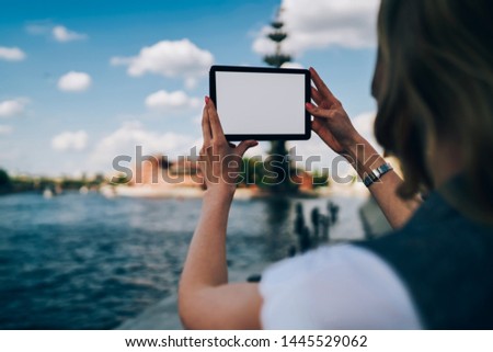 Back view of female person trying to make good picture on digital tablet with mock up screen for your promotional.Cropped image of woman's hands holding gadget with copy space for advertising