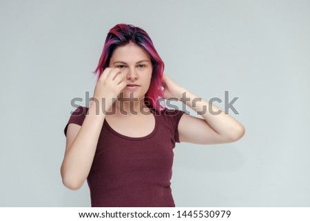Portrait to the waist of a young pretty girl teenager in a burgundy T-shirt with beautiful purple hair on a white background in the studio. Talking, smiling, showing hands with emotions.