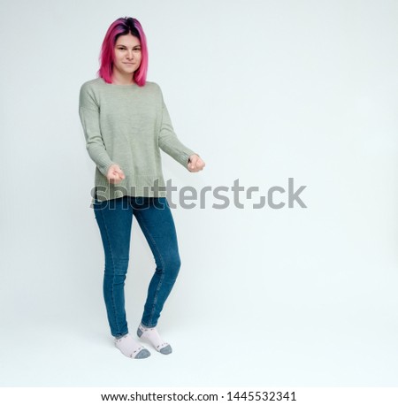 Full-length portrait of a young pretty teen girl with beautiful purple hair on a white background in the studio. Standing right in front of the camera, talking, smiling, showing hands with emotions.
