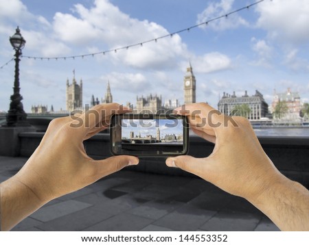 tourist holds up camera mobile at big ben in london england 