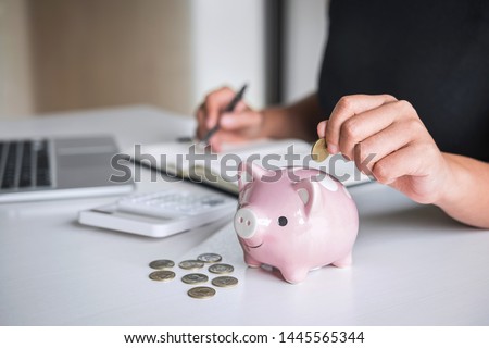 Woman putting golden coin in pink piggy bank for step up growing business to profit and saving with piggy bank, Saving money for future plan and retirement fund concept. Royalty-Free Stock Photo #1445565344