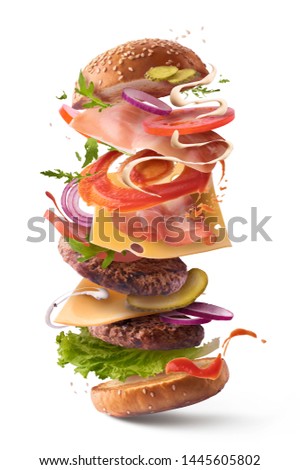 Delicious burger with flying ingredients isolated on white background