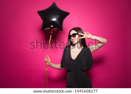 Portrait of caucasian girl wearing dress smiling and holding star balloon isolated over pink background