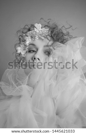 Fashion portrait of a  young woman with a bright eye creative make-up with flowers and curly hair